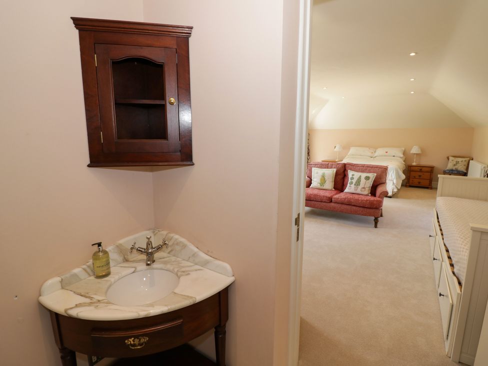 A bathroom with a sink and wall cabinet leading into a bedroom at The Stable Flat