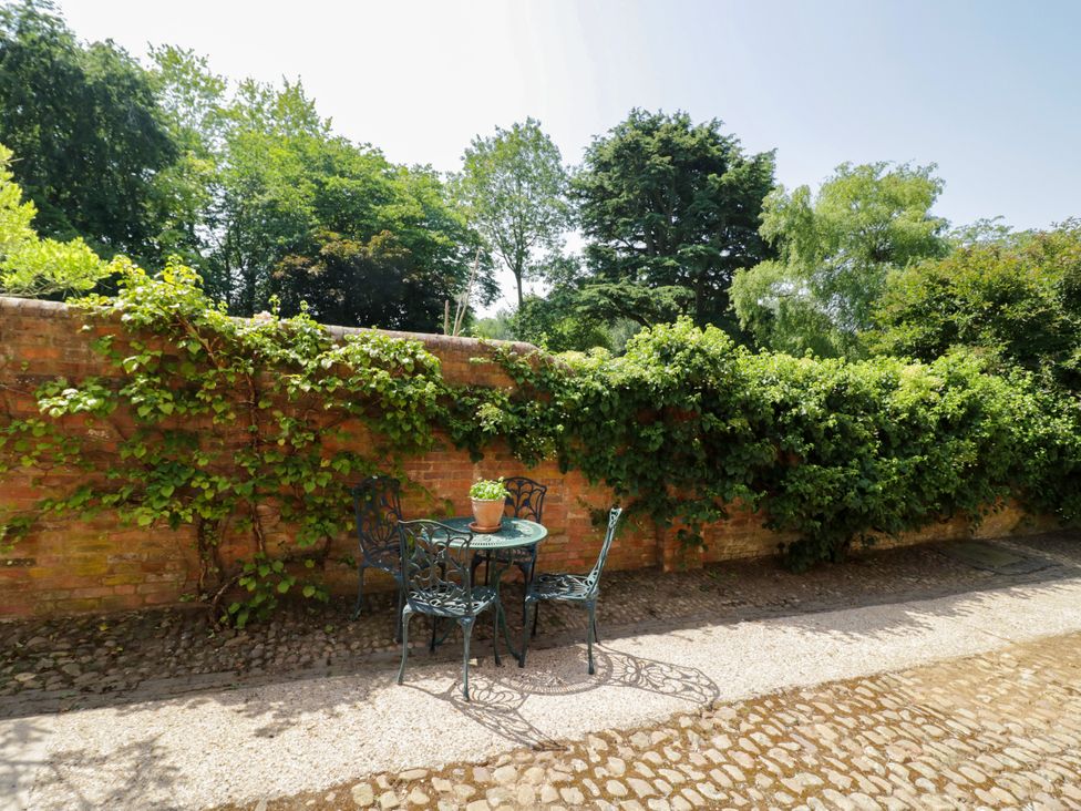 A garden with a table and chairs against a brick wall at The Stable Flat 