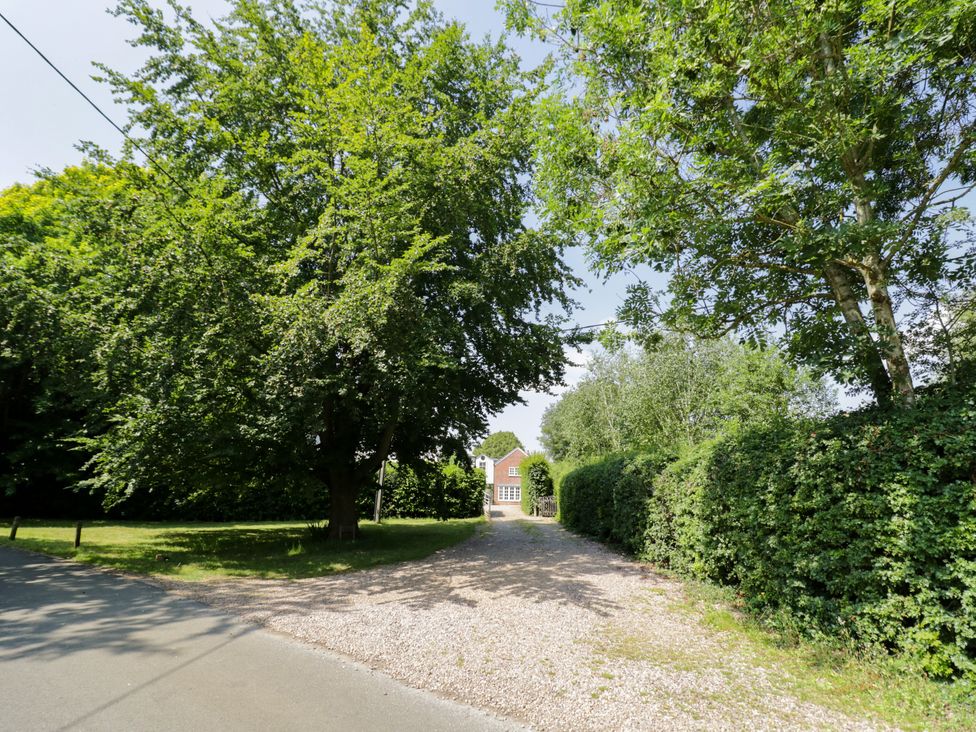 A driveway with trees and hedges leading to a house at The Stable Flat in 