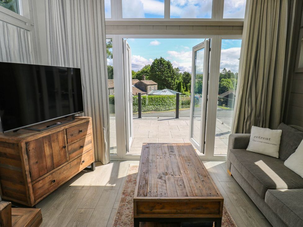 A living room with a television and a view of the outdoor patio at Dales Retreat Threshfield near Grassington