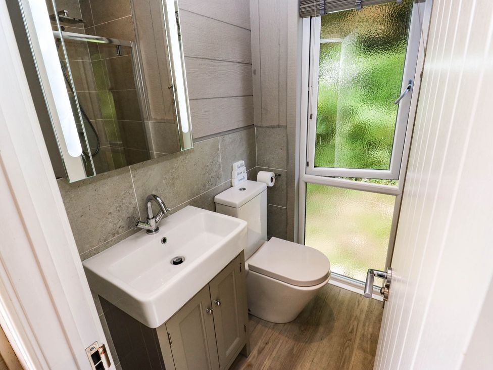 A bathroom with a sink, toilet, shower and window at Dales Retreat in Threshfield near Grassington