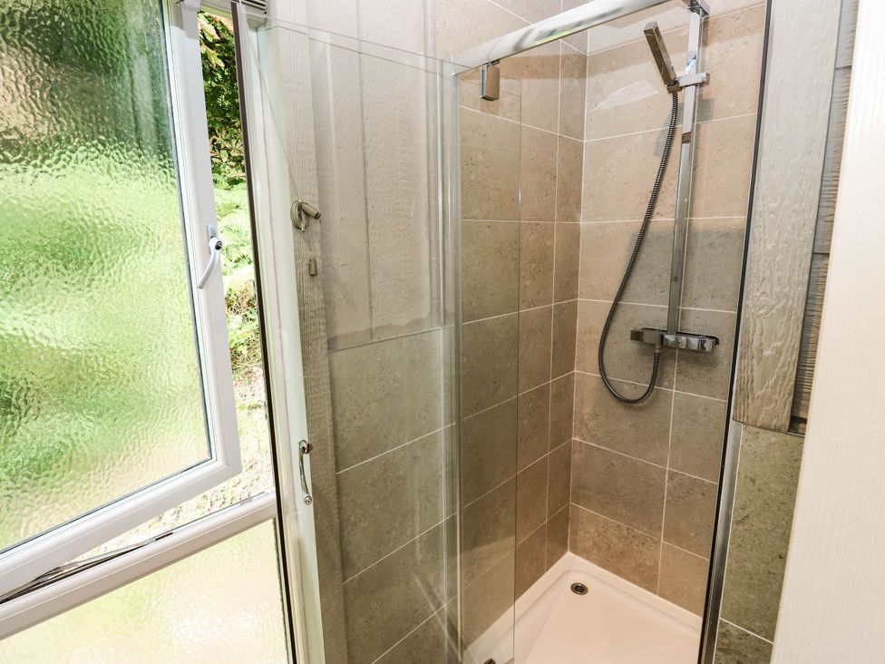 A shower with glass door and tile walls at Dales Retreat in Threshfield near Grassington