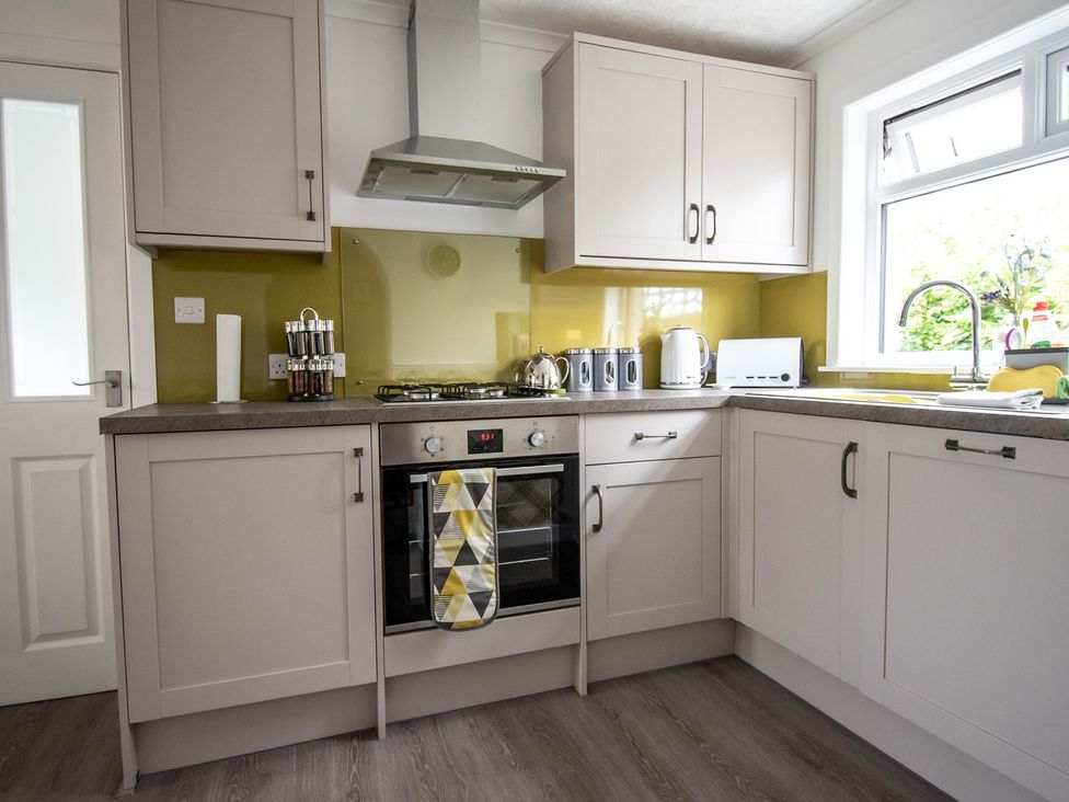 A kitchen with cabinets, stove, sink, and kettle at 
