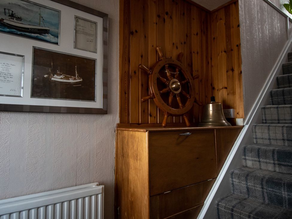 A hallway with photographs and a ship's wheel at 