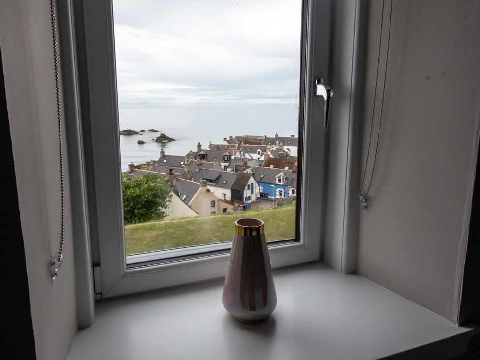 A vase on a window sill with a view of houses and the ocean at the property