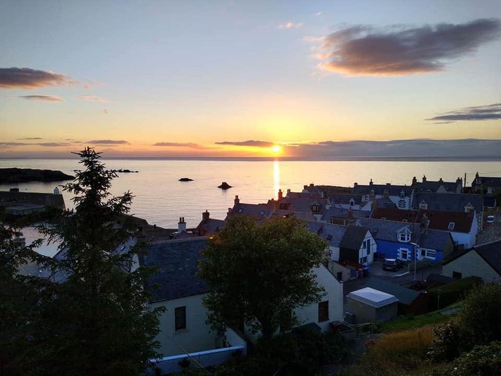 A view of a sunset over the sea with houses in the foreground