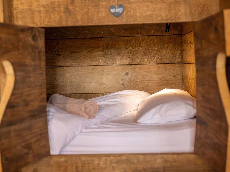 A sleeping area with bedding and pillows in a wooden frame at the accommodation
