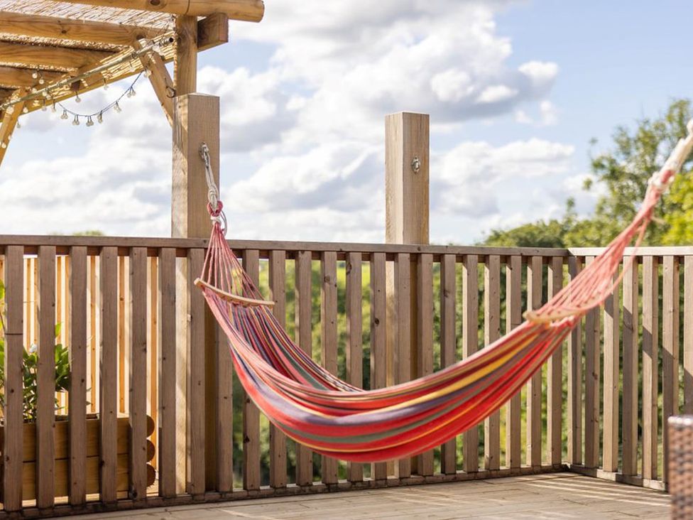 An outdoor space with a hammock and wooden railing at the property