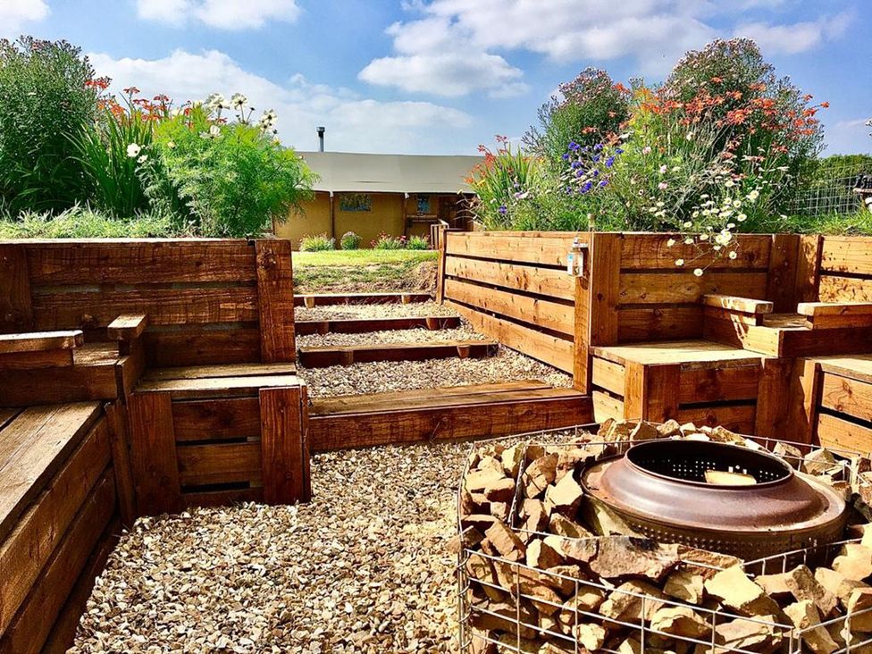 A garden with wooden seating and a fire pit at The Old Barn in Manchester