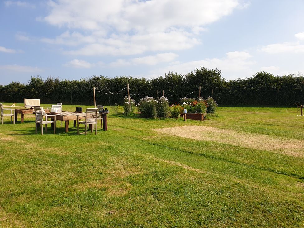 A garden with tables and chairs surrounded by plants and a fence