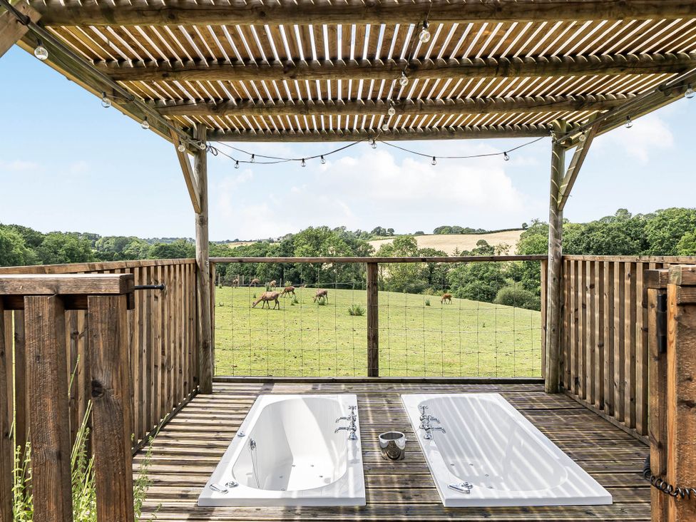 An outdoor area with hot tubs on a wooden deck at Luxury Safari Lodge Sleeps 4/6 Deer Park Dogs Ok Zeal Monachorum near Bow