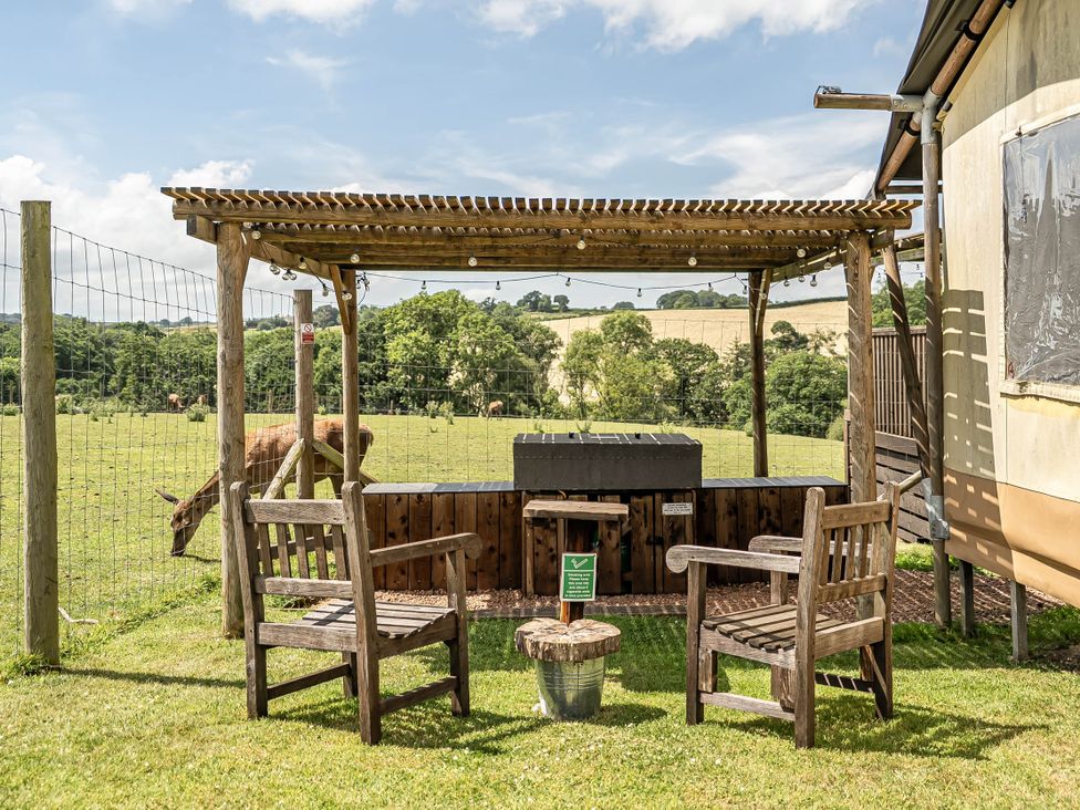 An outdoor seating area with wooden chairs and a fire pit at Luxury Safari Lodge Sleeps 4/6 Deer Park Dogs Ok Zeal Monachorum near Bow