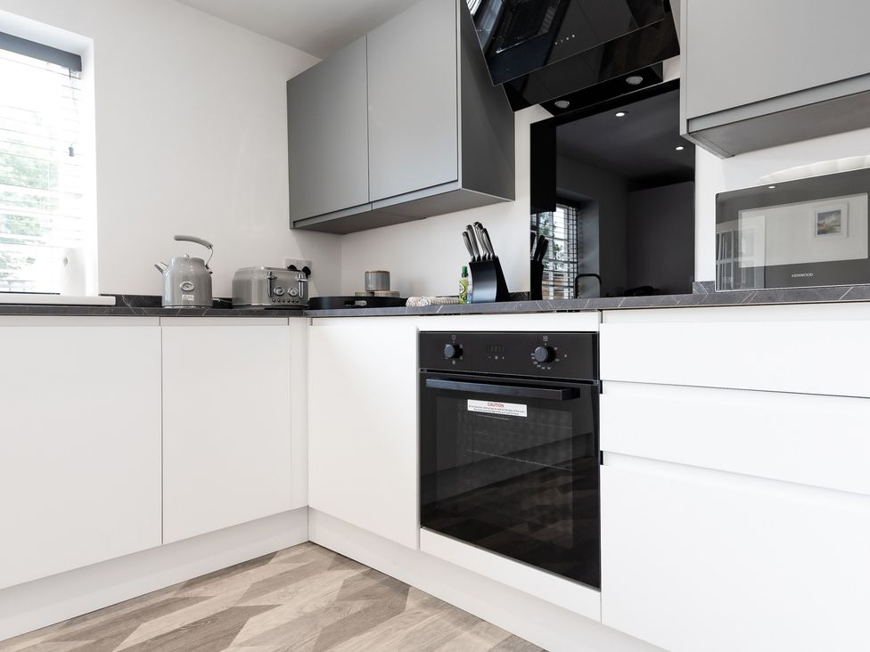 A kitchen with an oven, microwave, kettle, and toaster at 