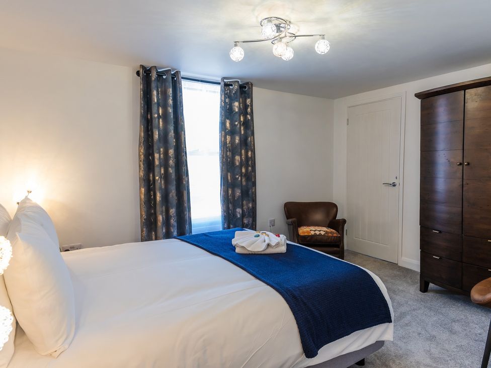 A bedroom with a bed and wardrobe with an armchair at The Old Barn in Manchester