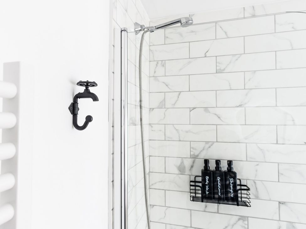 A bathroom with a shower and a shelf containing body wash and shampoo