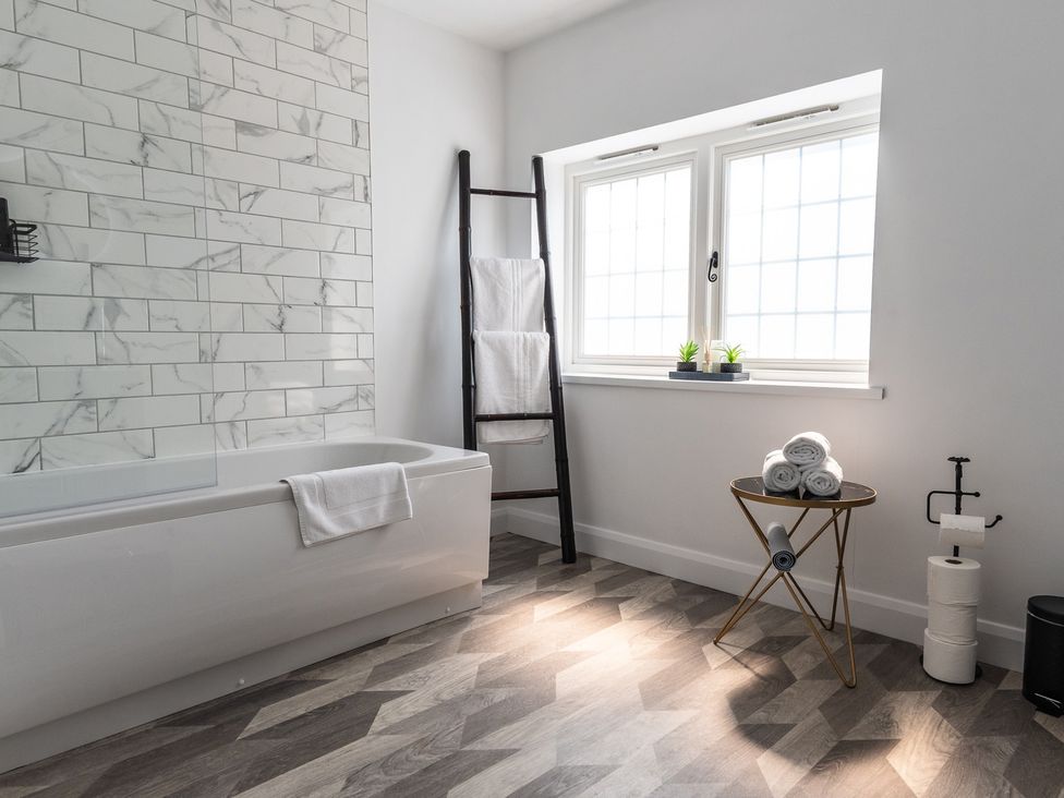 A bathroom with a bathtub, towels, and a window at the property