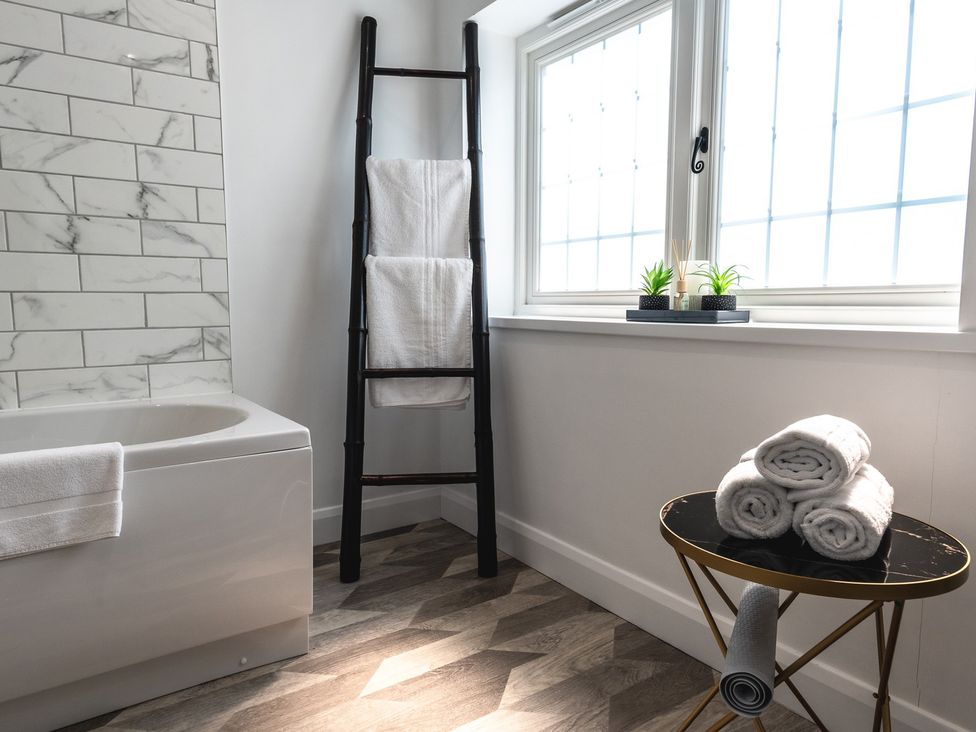 A bathroom with a bathtub, towels on a rack, and a window at the property