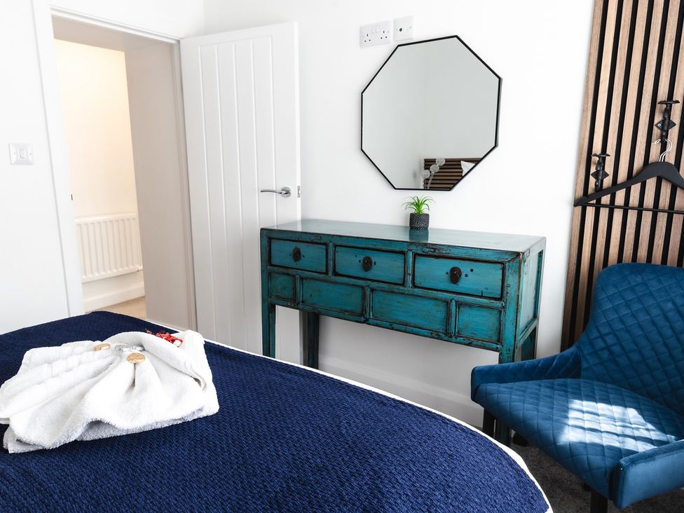 A bedroom with a blue bedspread and furniture at 
