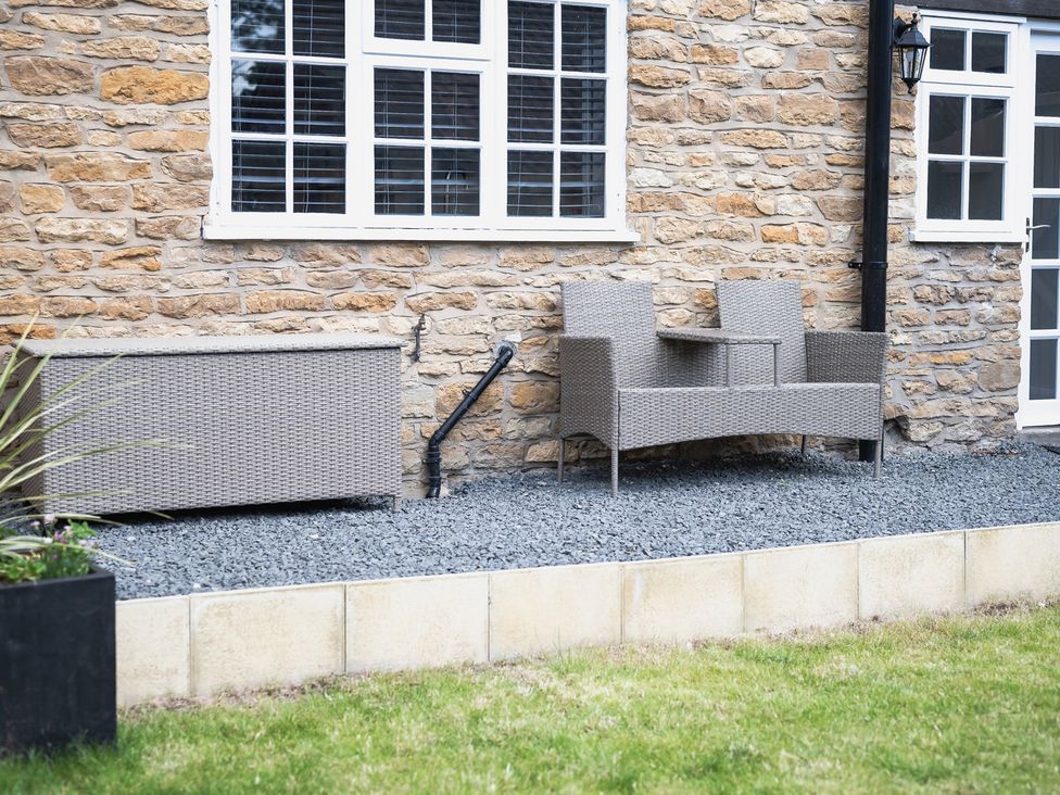 A garden with a loveseat and planter near a stone wall at the property in the location