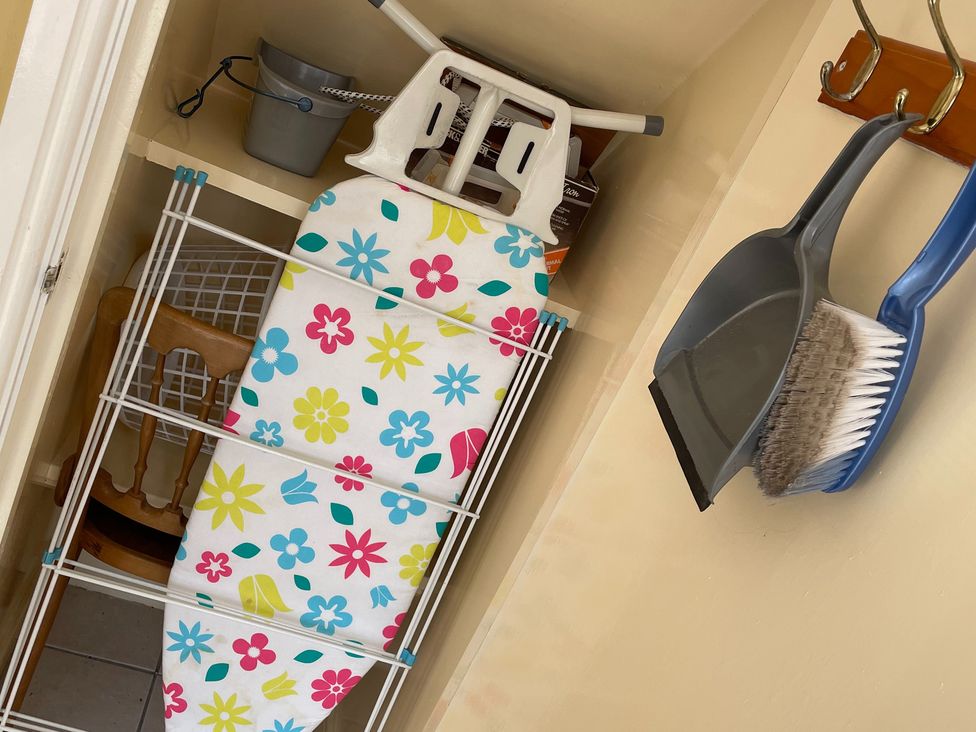 A laundry room with an ironing board and cleaning supplies in a closet