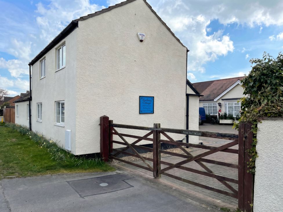 A house with a sign and a wooden gate at Railway Cottage