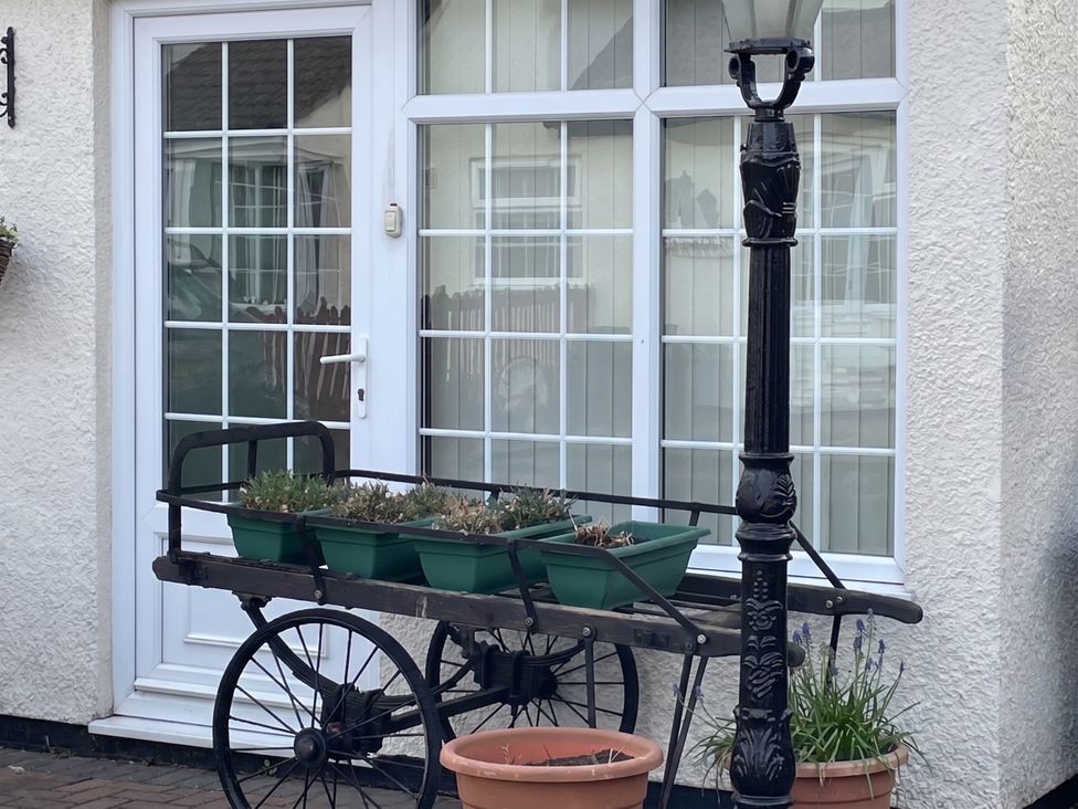 A plant stand with potted plants and a lamppost in front of a door and window