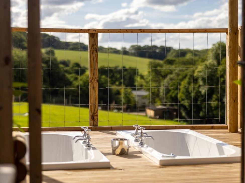 Two bathtubs on a deck overlooking fields at a property