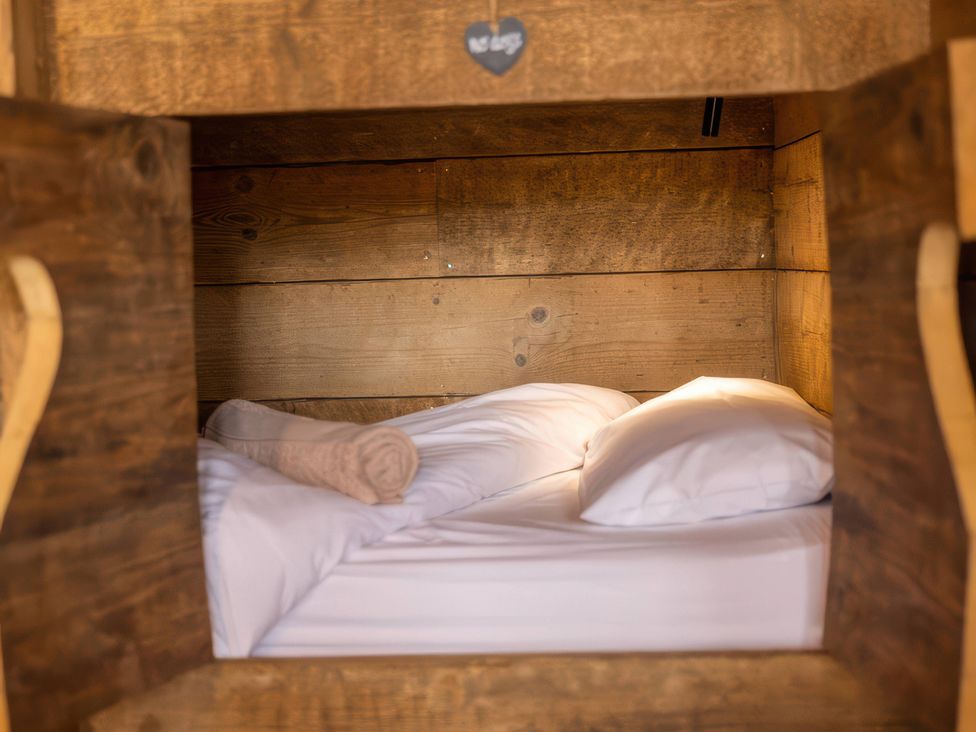 A bed with pillows and a blanket in a wooden structure
