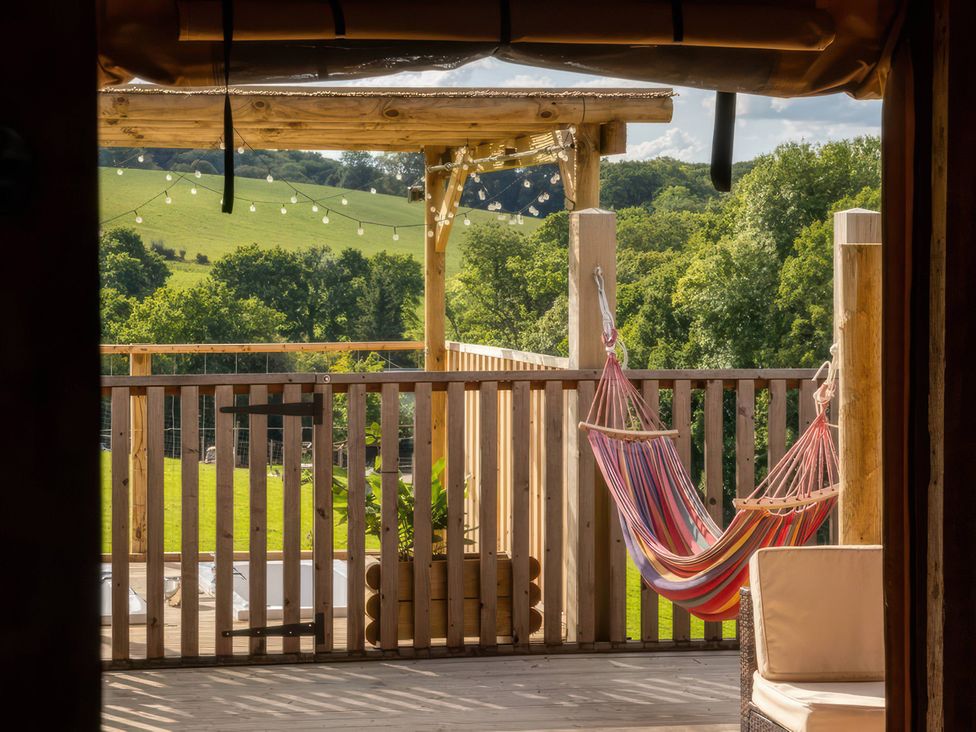 A deck with a hammock and wooden railing at an outdoor space