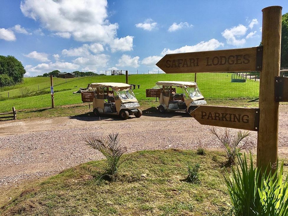A parking area with tuk-tuks and a signpost at a safari lodge