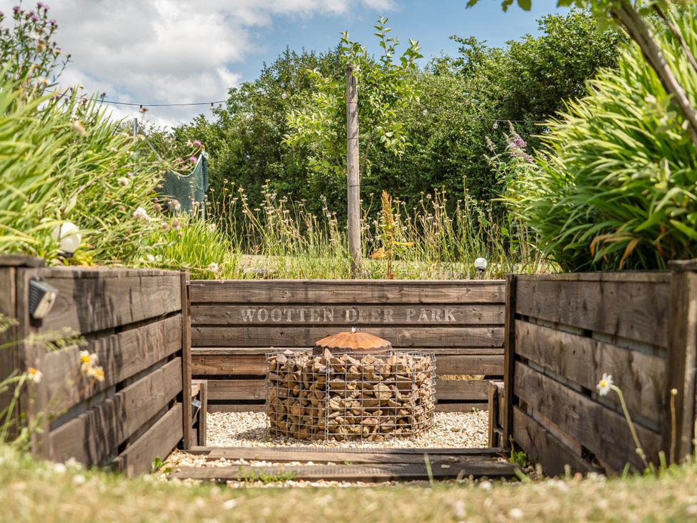A garden with a fire pit and wood enclosure at Luxury Safari Lodge Sleeps 4/6 Deer Park Dogs Ok Zeal Monachorum near Bow