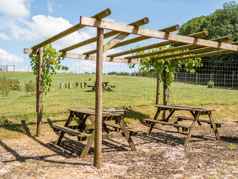 An outdoor area with picnic tables under a pergola at Luxury Safari Lodge Sleeps 4/6 Deer Park Dogs Ok Zeal Monachorum near Bow