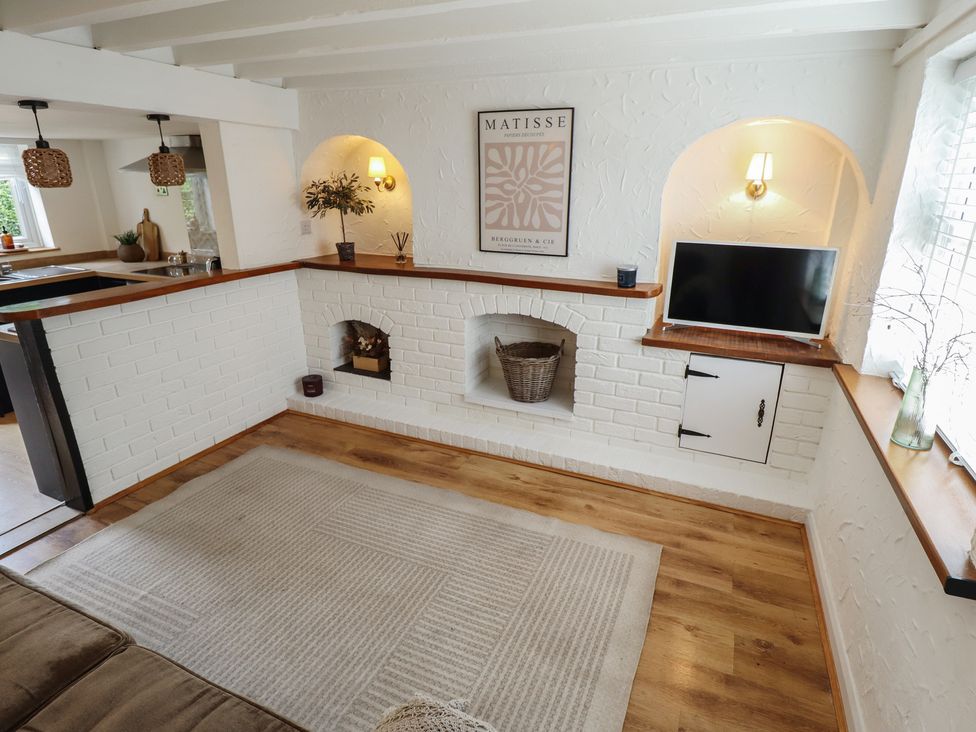 A living room with a television and a decorative plant at Pax Cottage
