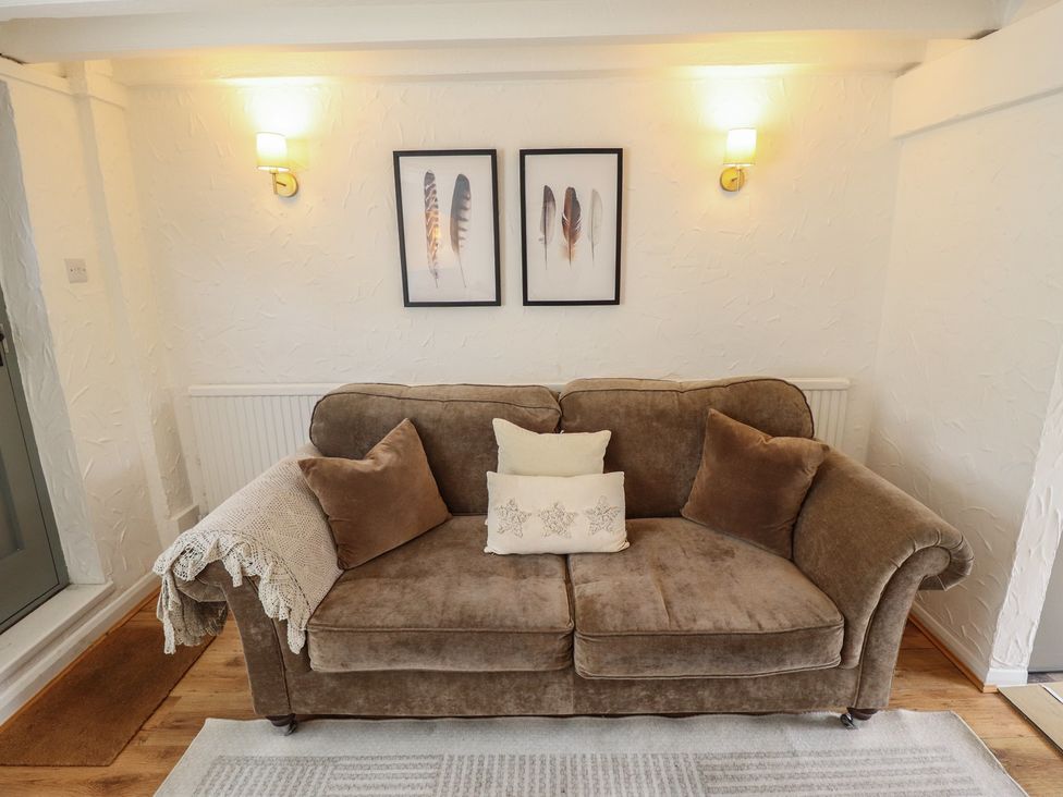 A living room with a sofa, wall art, and a radiator at Pax Cottage