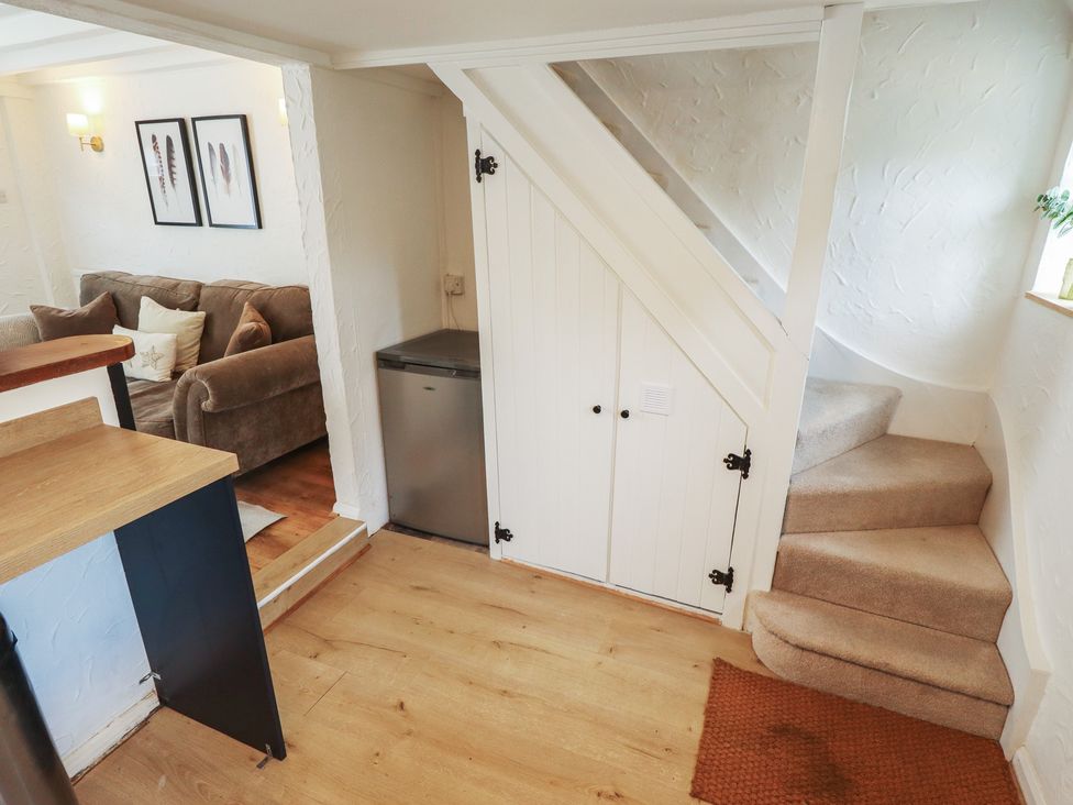 A living room with a sofa and staircase at Pax Cottage