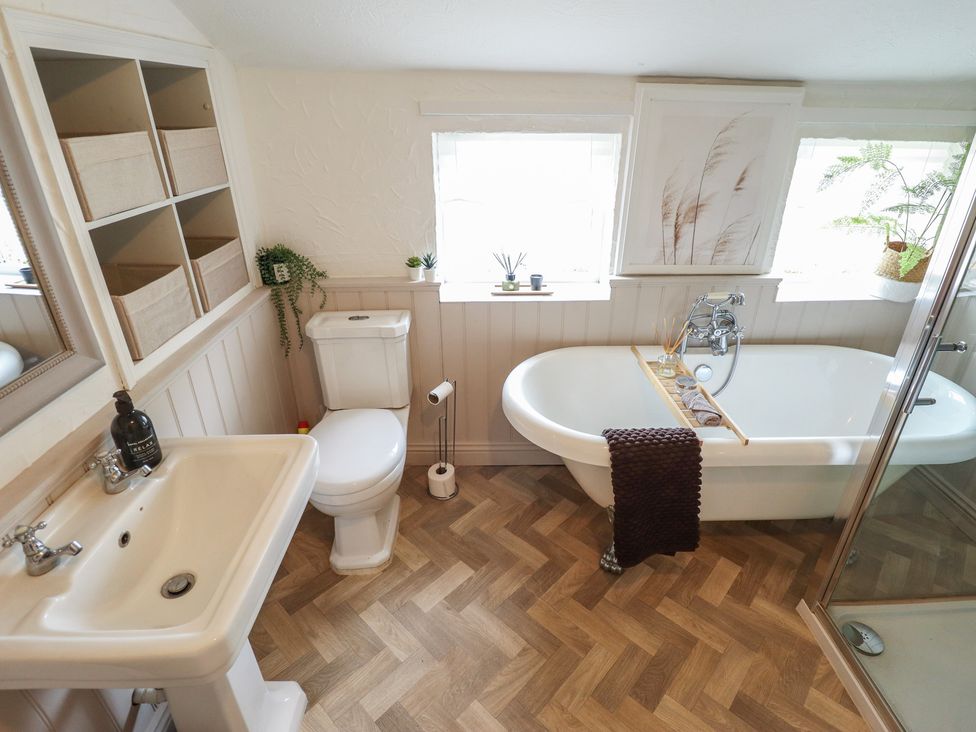 A bathroom with a bathtub, toilet, sink, and shower at Pax Cottage