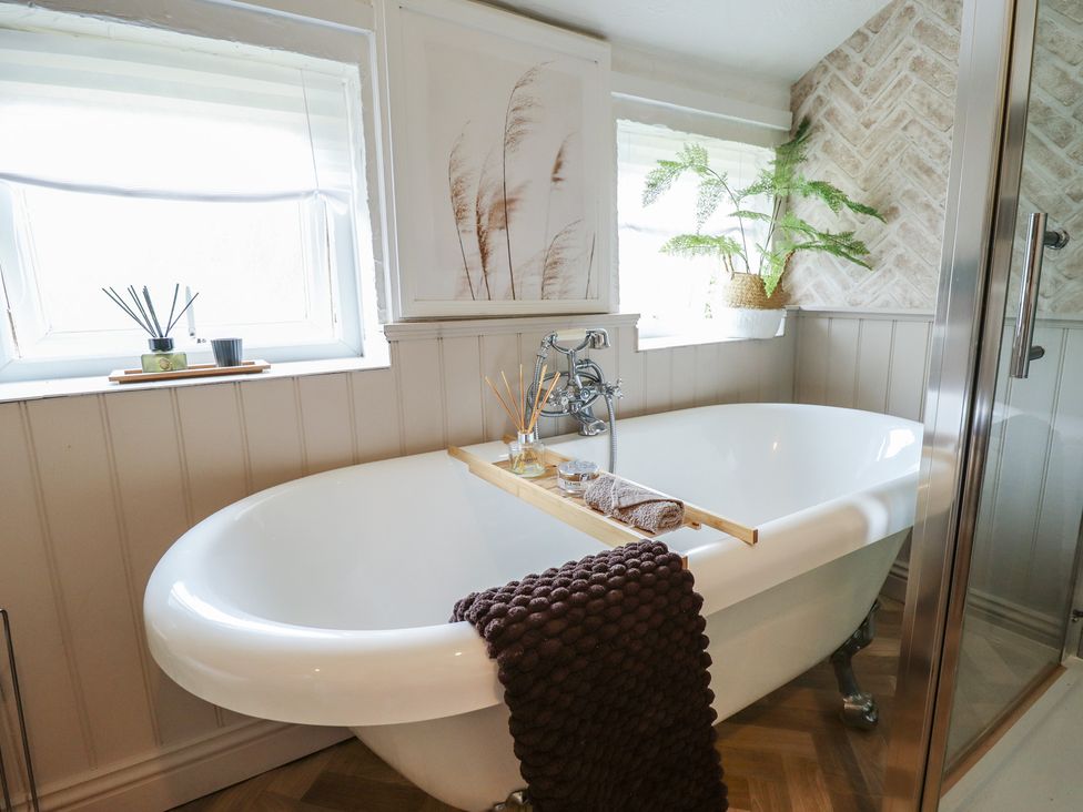 A bathtub with a towel and decorative items at Pax Cottage