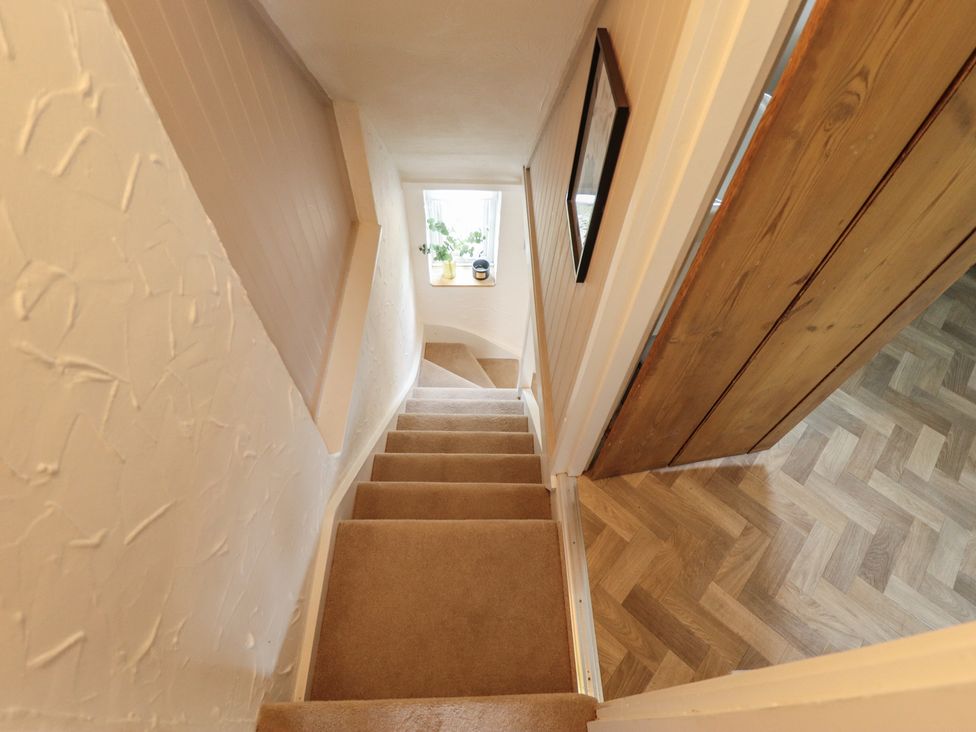 A staircase leading down to a hallway with a window and a door at Pax Cottage