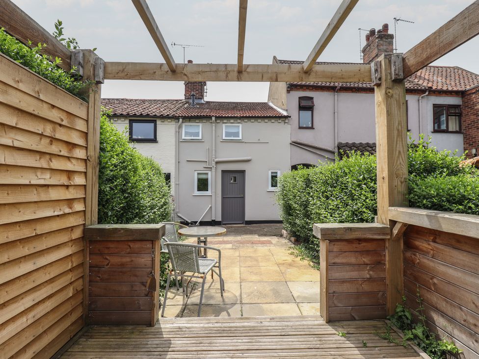 A garden with a wooden pergola and a table with chairs at Pax Cottage