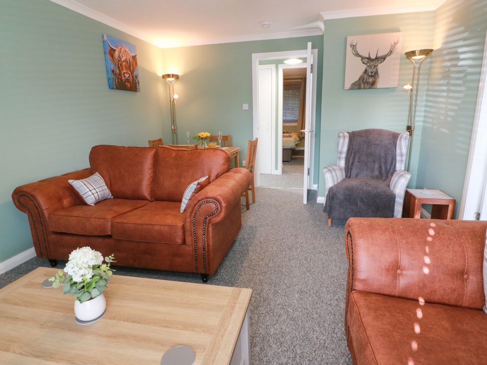 A living room with a sofa, armchair, and dining area at No.31 Craigard Road