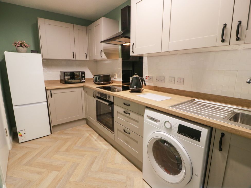 A kitchen with appliances including a refrigerator and washing machine at No.31 Craigard Road
