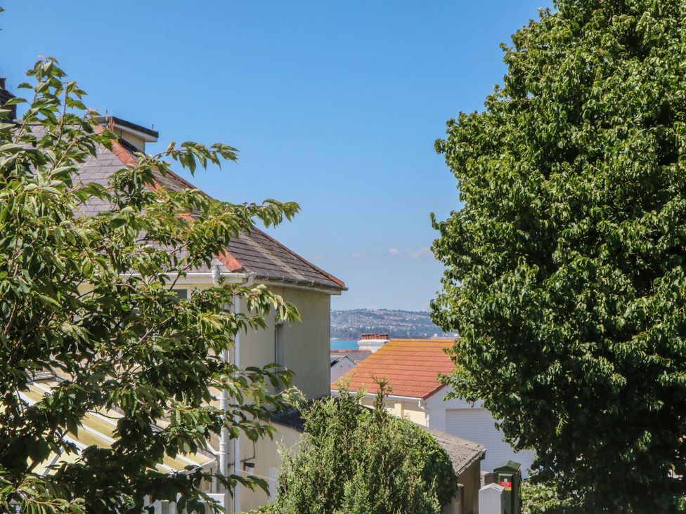 A view of houses and trees with sea in the background at 3 Heath Park Brixham