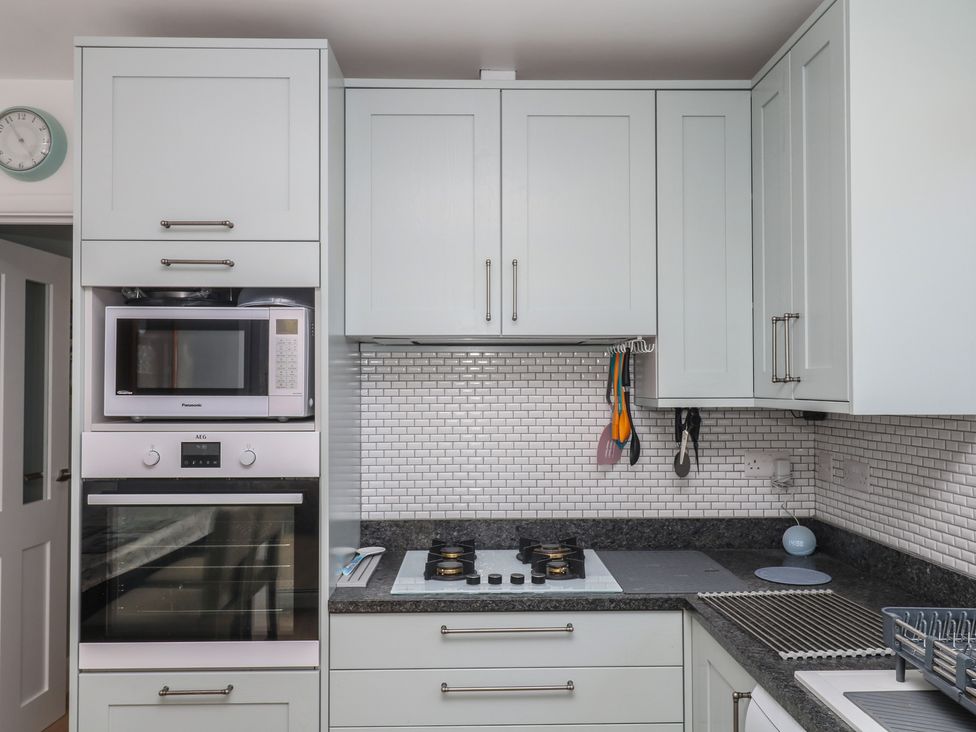 A kitchen with cabinets, microwave, oven, and stove at 3 Heath Park in Brixham