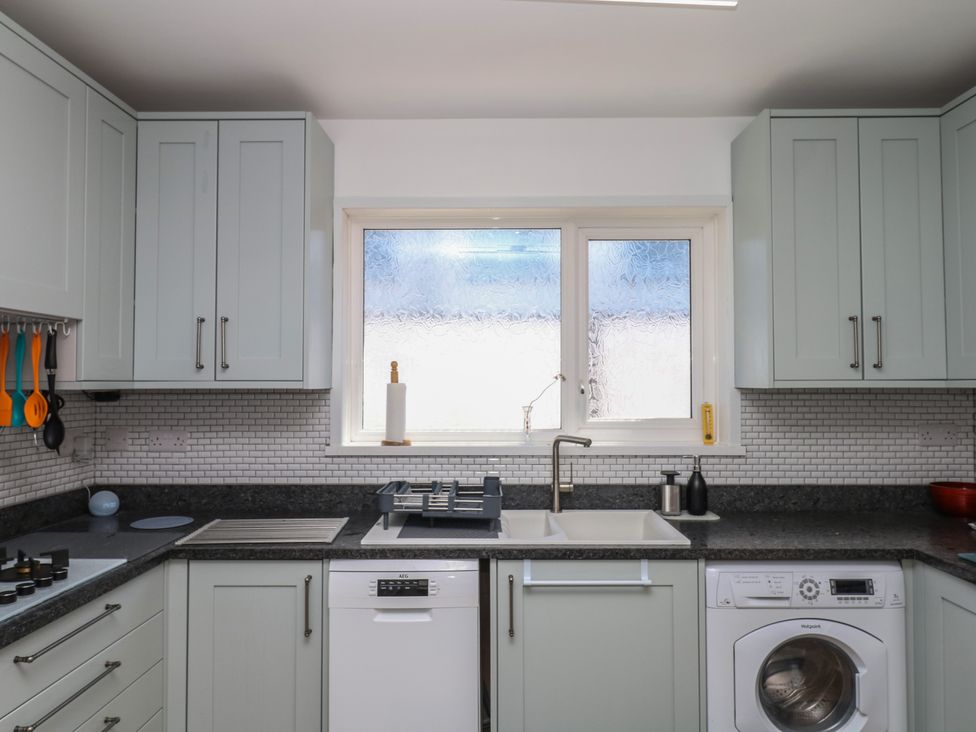 A kitchen with cabinets, sink, dishwasher, and window at 3 Heath Park Brixham