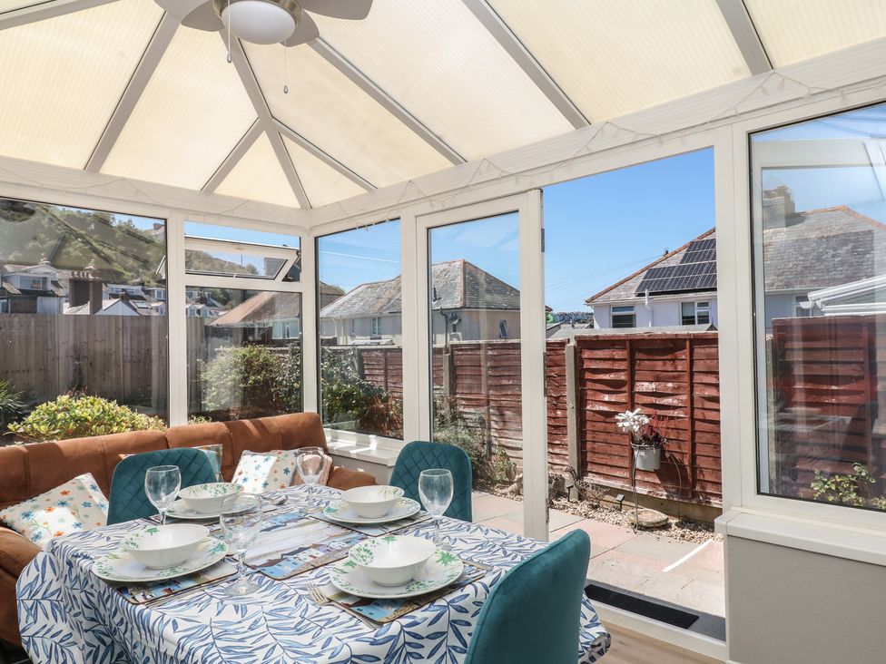 A conservatory with a table and chairs at 3 Heath Park in Brixham