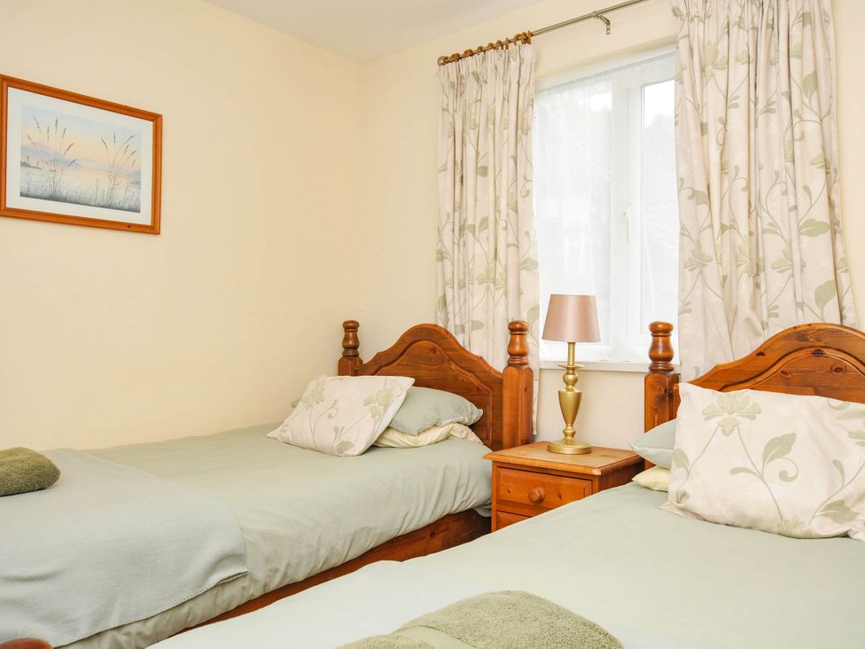 A bedroom with two beds and a nightstand at No.122 Hengar Holiday Park near St Tudy