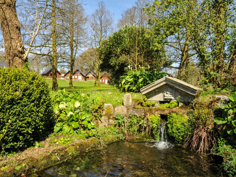 A garden with a water feature and trees at No.122 Hengar Holiday Park near St Tudy