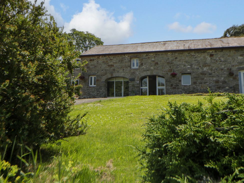 A stone building with windows and a door in a garden at The Cart House in Pontsian