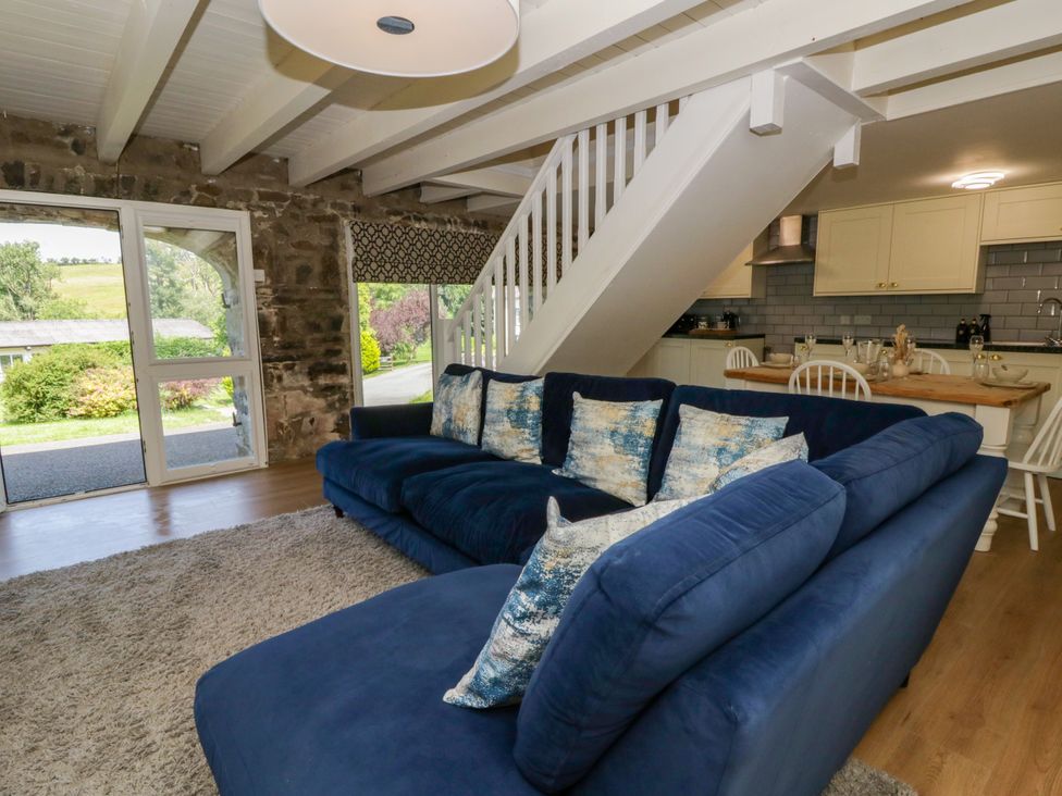 A living room with a sofa and kitchen area at The Cart House in Pontsian