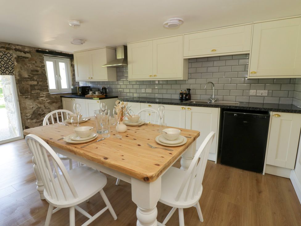A kitchen with a wooden table and white chairs at The Cart House in Pontsian